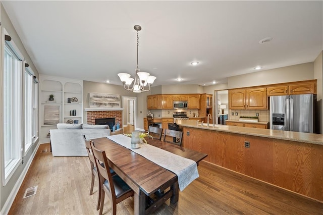 14450 W 146th Ter, Olathe, KS 66062 - dining room featuring a chandelier, light wood-style flooring, recessed lighting, a brick fireplace, and baseboards