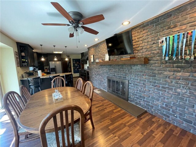 1211 N 6th St, Hiawatha, KS 66434 - dining area featuring brick wall, a ceiling fan, a fireplace, and wood finished floors