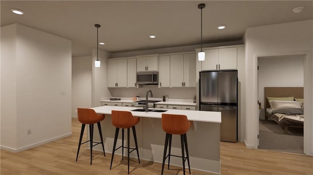 18305 W 166th St, Olathe, KS 66062 - kitchen with stainless steel appliances, a center island with sink, a breakfast bar area, white cabinetry, and light countertops
