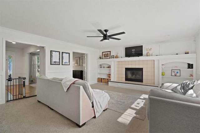 8443 Mettee St, Lenexa, KS 66219 - living area featuring crown molding, ceiling fan, carpet floors, a tiled fireplace, and built in shelves