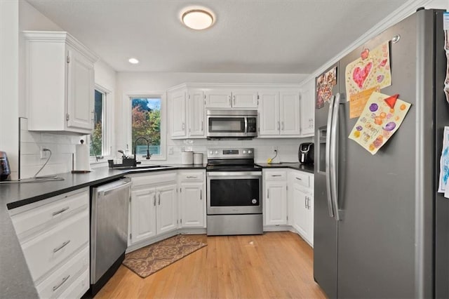 8443 Mettee St, Lenexa, KS 66219 - kitchen with appliances with stainless steel finishes, a sink, dark countertops, white cabinetry, and light wood-type flooring