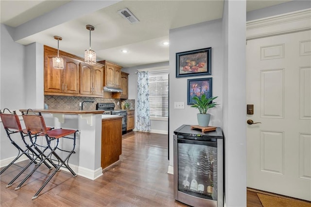 15828 W 61st St, Shawnee, KS 66217 - kitchen featuring range with electric cooktop, beverage cooler, under cabinet range hood, a kitchen breakfast bar, and brown cabinetry