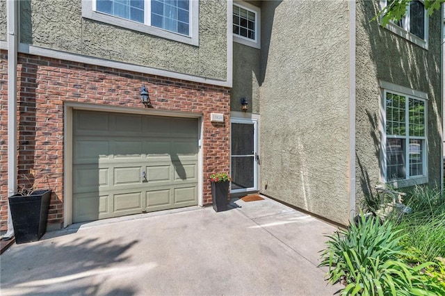15828 W 61st St, Shawnee, KS 66217 - property entrance featuring stucco siding, a garage, brick siding, and driveway