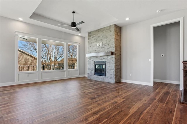 12425 NW Empress St, Platte City, MO 64079 - unfurnished living room featuring dark wood-style flooring, ceiling fan, a stone fireplace, baseboards, and recessed lighting