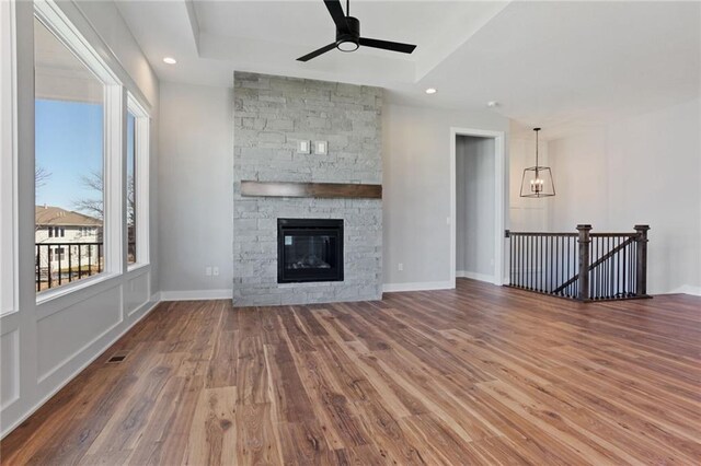 12425 NW Empress St, Platte City, MO 64079 - unfurnished living room featuring wood finished floors, ceiling fan, a fireplace, a tray ceiling, and recessed lighting