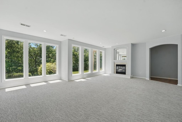 165 NE Hidden Ridge Ln, Lees Summit, MO 64064 - unfurnished living room featuring carpet, a tile fireplace, baseboards, recessed lighting, and arched walkways