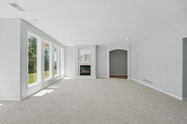 165 NE Hidden Ridge Ln, Lees Summit, MO 64064 - unfurnished living room with arched walkways, carpet flooring, baseboards, a glass covered fireplace, and recessed lighting
