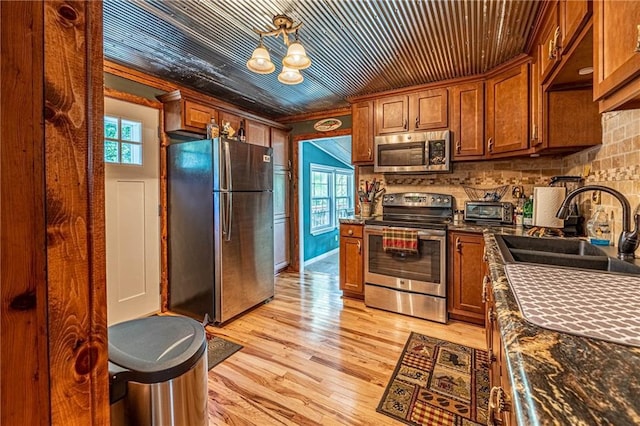 26406 Waterview Dr, Warsaw, MO 65355 - kitchen featuring appliances with stainless steel finishes, a sink, brown cabinets, ornamental molding, and light wood finished floors