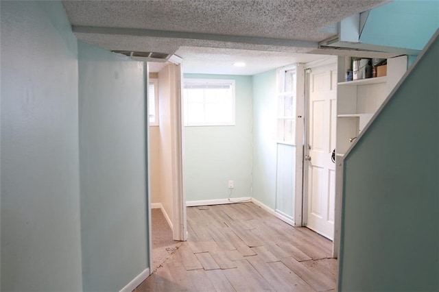 816 S Huttig Ave, Independence, MO 64053 - below grade area with baseboards, light wood-style flooring, and a textured ceiling