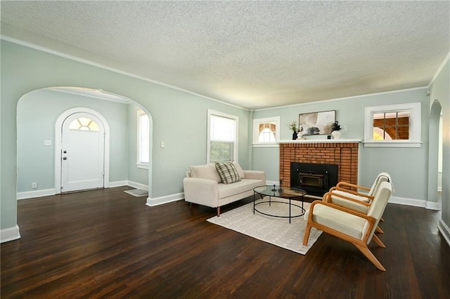 314 N Crysler Ave, Independence, MO 64050 - living room with arched walkways, a textured ceiling, ornamental molding, wood finished floors, and a fireplace