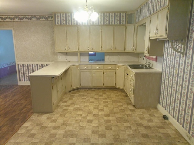220 W State St, Erie, KS 66733 - kitchen featuring wallpapered walls, a sink, a peninsula, light countertops, and a chandelier