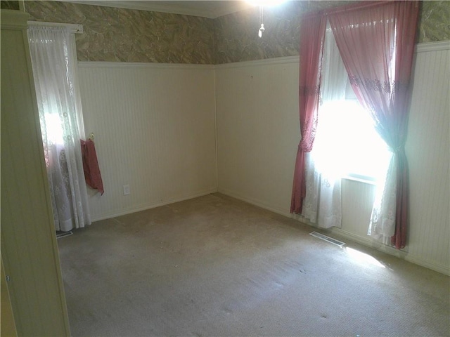 220 W State St, Erie, KS 66733 - carpeted empty room with wallpapered walls and a wainscoted wall