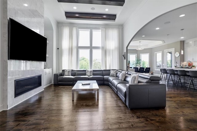 8605 NE Shl Creek Pkwy, Kansas City, MO 64157 - living area featuring a premium fireplace, dark wood-style floors, arched walkways, a raised ceiling, and baseboards