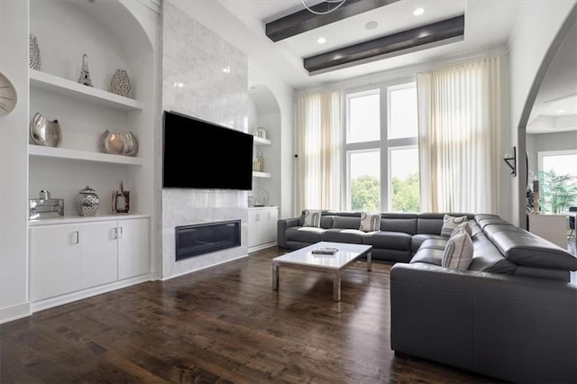 8605 NE Shl Creek Pkwy, Kansas City, MO 64157 - living area featuring built in features, a glass covered fireplace, dark wood-style floors, and a raised ceiling