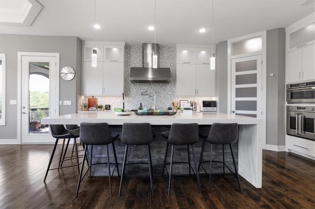 8605 NE Shl Creek Pkwy, Kansas City, MO 64157 - kitchen featuring wall chimney range hood, dark wood-style floors, backsplash, and recessed lighting