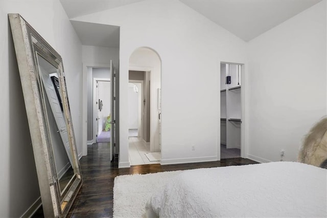 8605 NE Shl Creek Pkwy, Kansas City, MO 64157 - bedroom featuring dark wood finished floors, vaulted ceiling, baseboards, arched walkways, and a spacious closet