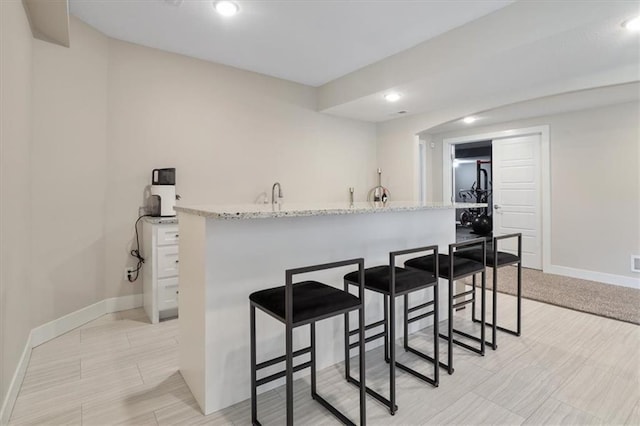 8605 NE Shl Creek Pkwy, Kansas City, MO 64157 - kitchen with baseboards, a kitchen breakfast bar, recessed lighting, and light stone counters
