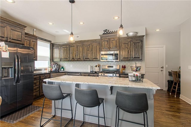 25383 W 144th Ct, Olathe, KS 66061 - kitchen featuring appliances with stainless steel finishes, tasteful backsplash, dark wood-type flooring, a kitchen breakfast bar, and recessed lighting