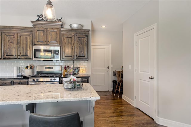 25383 W 144th Ct, Olathe, KS 66061 - kitchen with appliances with stainless steel finishes, decorative backsplash, dark wood-style floors, light stone counters, and recessed lighting