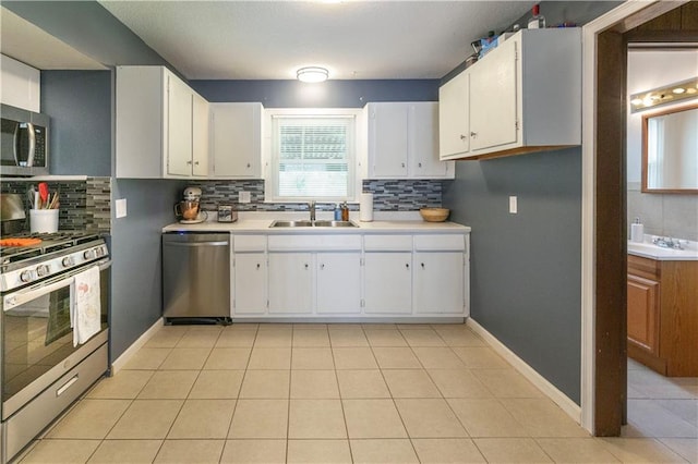 8401 England St, Overland Park, KS 66212 - kitchen featuring appliances with stainless steel finishes, a sink, backsplash, and white cabinetry