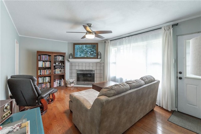 8401 England St, Overland Park, KS 66212 - living area featuring a ceiling fan, a tiled fireplace, hardwood / wood-style flooring, and ornamental molding