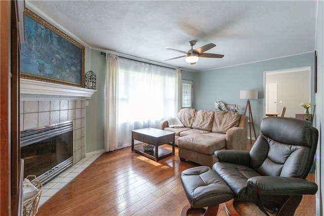 8401 England St, Overland Park, KS 66212 - living area with crown molding, ceiling fan, light wood-style floors, a textured ceiling, and a tile fireplace
