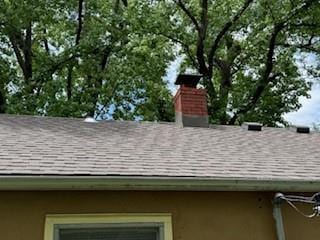 7231 Forest Ave, Kansas City, MO 64131 - exterior view of roof with shingles, a chimney, gutters, and a downspout