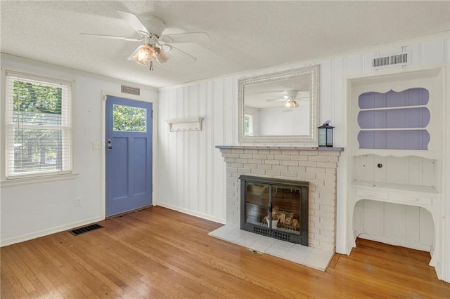 10916 Grandview Rd, Kansas City, MO 64137 - unfurnished living room featuring a ceiling fan, a textured ceiling, wood finished floors, baseboards, and a fireplace