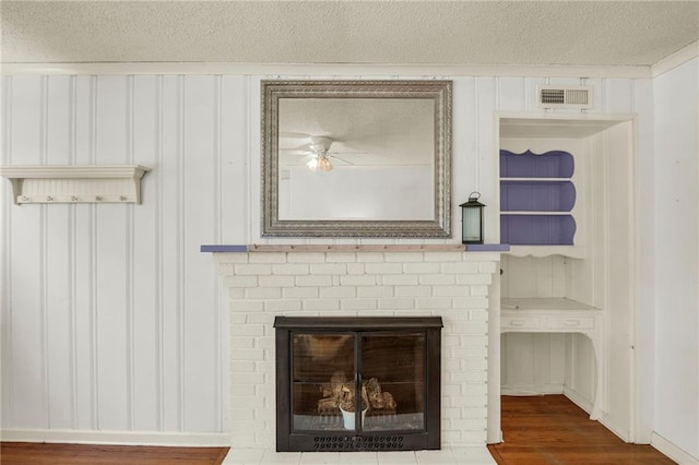 10916 Grandview Rd, Kansas City, MO 64137 - detailed view of a textured ceiling, ceiling fan, wood finished floors, a brick fireplace, and a decorative wall