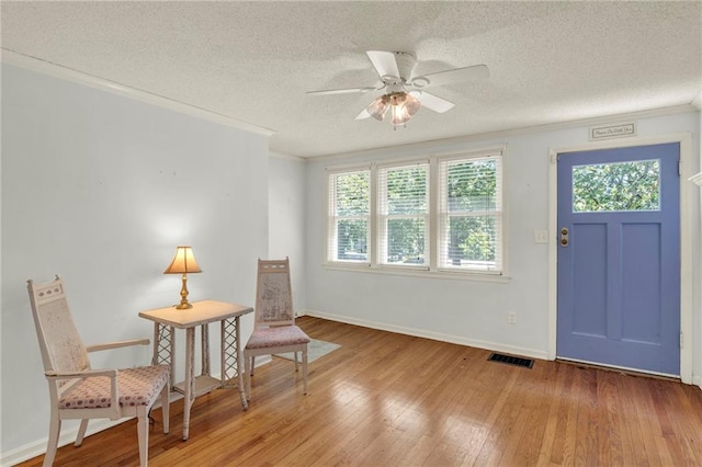 10916 Grandview Rd, Kansas City, MO 64137 - sitting room with light wood-type flooring, a textured ceiling, a ceiling fan, baseboards, and crown molding