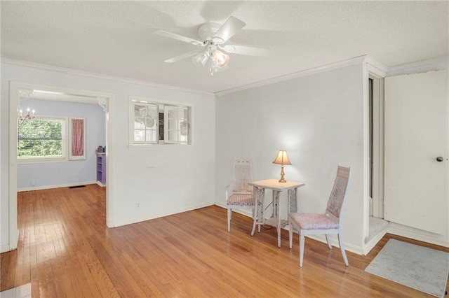 10916 Grandview Rd, Kansas City, MO 64137 - living area featuring light wood-style flooring, crown molding, ceiling fan, baseboards, and a textured ceiling