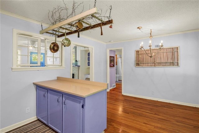 10916 Grandview Rd, Kansas City, MO 64137 - kitchen featuring blue cabinetry, a chandelier, a textured ceiling, crown molding, and a peninsula