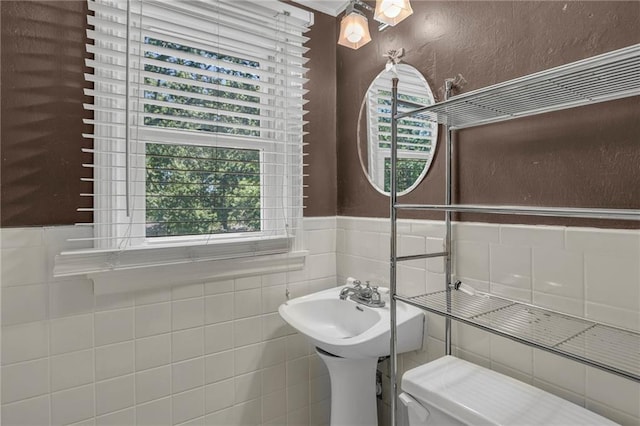 10916 Grandview Rd, Kansas City, MO 64137 - bathroom featuring a wainscoted wall, tile walls, and toilet