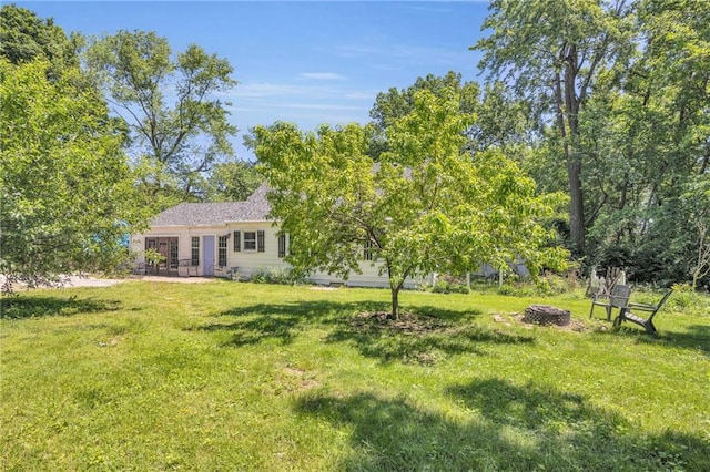 10916 Grandview Rd, Kansas City, MO 64137 - view of grassy yard with an outdoor fire pit