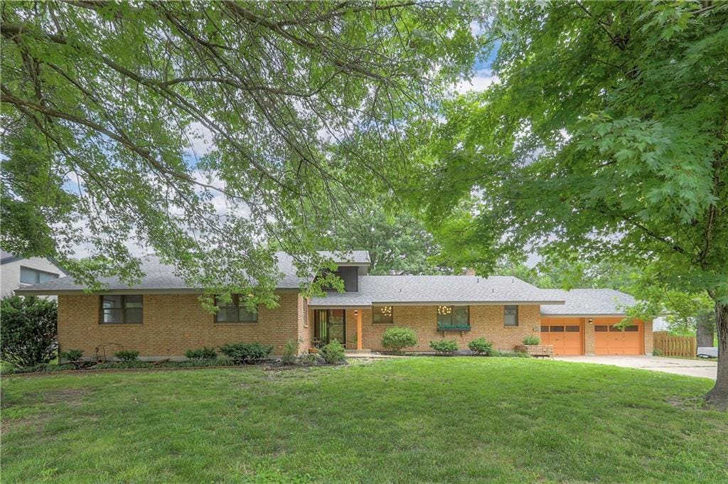 4605 N Main St, Kansas City, MO 64116 - view of front of house with an attached garage, a front lawn, concrete driveway, and brick siding