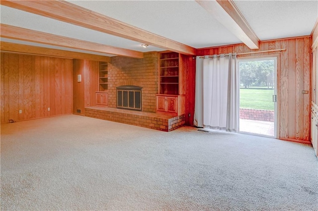 917 Country Club Dr, Butler, MO 64730 - unfurnished living room with carpet floors, beamed ceiling, wood walls, a brick fireplace, and a textured ceiling