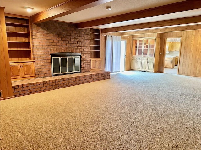 917 Country Club Dr, Butler, MO 64730 - unfurnished living room featuring beamed ceiling, carpet, a fireplace, wooden walls, and built in shelves