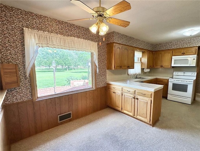 917 Country Club Dr, Butler, MO 64730 - kitchen with white appliances, wainscoting, a peninsula, tile countertops, and wooden walls