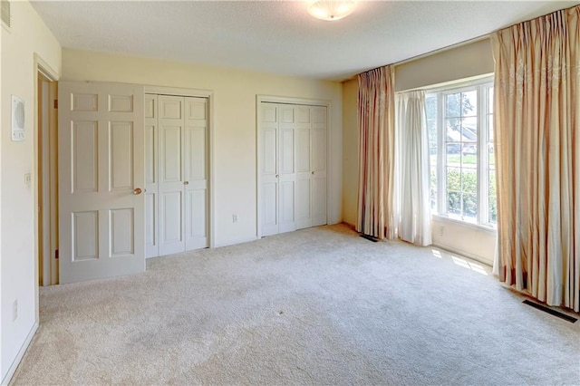 917 Country Club Dr, Butler, MO 64730 - unfurnished bedroom featuring carpet flooring, multiple windows, multiple closets, and a textured ceiling