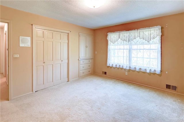 917 Country Club Dr, Butler, MO 64730 - unfurnished bedroom featuring a textured ceiling, light colored carpet, and a closet