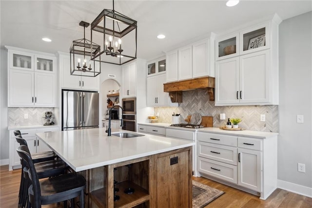 1108 NE Goshen Ct, Lees Summit, MO 64064 - kitchen with a sink, stainless steel appliances, an island with sink, backsplash, and arched walkways