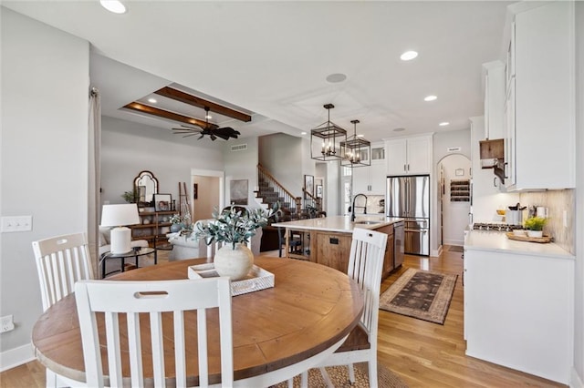 1108 NE Goshen Ct, Lees Summit, MO 64064 - dining room featuring stairs, light wood-type flooring, recessed lighting, a ceiling fan, and a chandelier