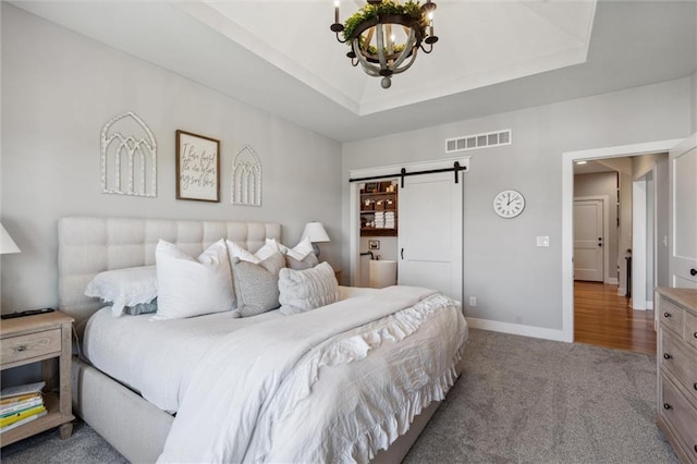 1108 NE Goshen Ct, Lees Summit, MO 64064 - bedroom featuring a barn door, a chandelier, carpet flooring, baseboards, and a tray ceiling
