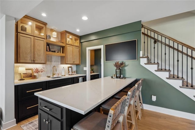 1108 NE Goshen Ct, Lees Summit, MO 64064 - kitchen with a sink, a breakfast bar area, light wood-style flooring, baseboards, and light countertops
