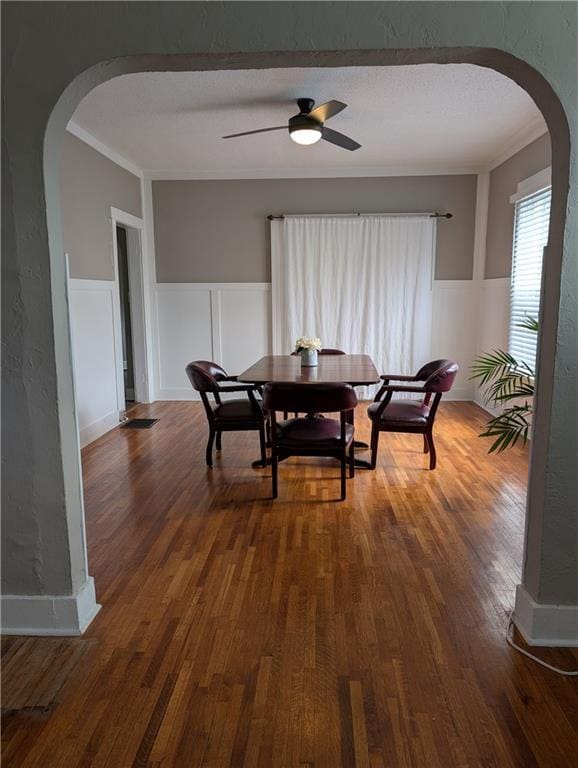 117 W N St, Warrensburg, MO 64093 - dining space featuring arched walkways, wood finished floors, wainscoting, ceiling fan, and crown molding