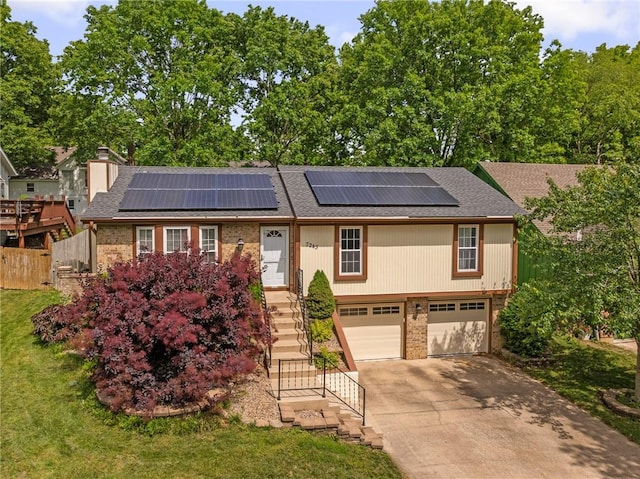 7243 Rene St, Shawnee, KS 66216 - view of front of home featuring brick siding, an attached garage, concrete driveway, stairs, and roof mounted solar panels