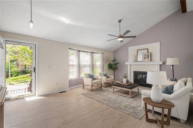 7243 Rene St, Shawnee, KS 66216 - living room with light wood-style floors, a textured ceiling, a tiled fireplace, lofted ceiling, and ceiling fan
