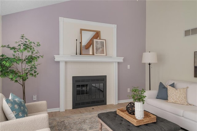 7243 Rene St, Shawnee, KS 66216 - living area featuring wood finished floors, baseboards, a tiled fireplace, and vaulted ceiling