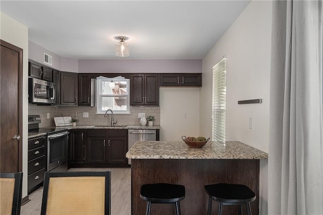 7243 Rene St, Shawnee, KS 66216 - kitchen with appliances with stainless steel finishes, a sink, a peninsula, tasteful backsplash, and light stone countertops
