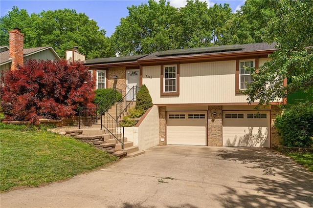 7243 Rene St, Shawnee, KS 66216 - view of front of house with asphalt driveway, an attached garage, solar panels, brick siding, and a front yard